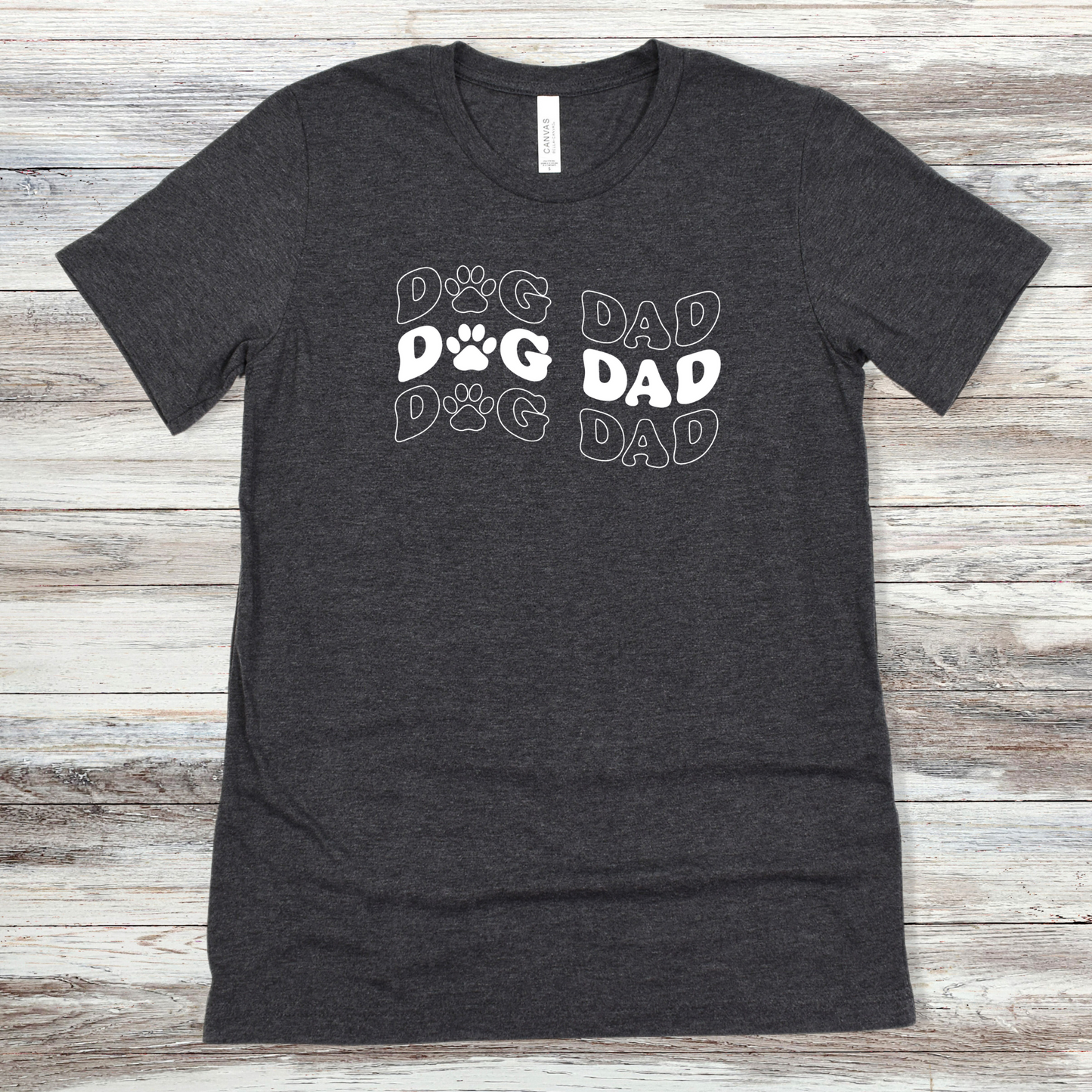 Text reading "Dog Dad" on a Dark Grey Heather Tee